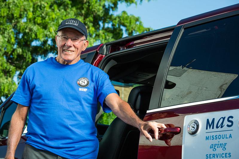Man wearing a baseball cap and smiling while opening a sliding van door.