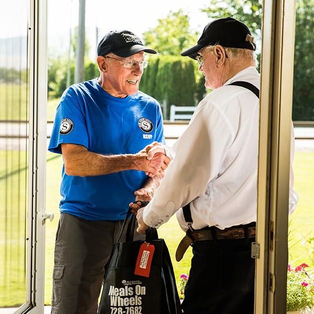 Man volunteers to deliver meals to an elderly man.