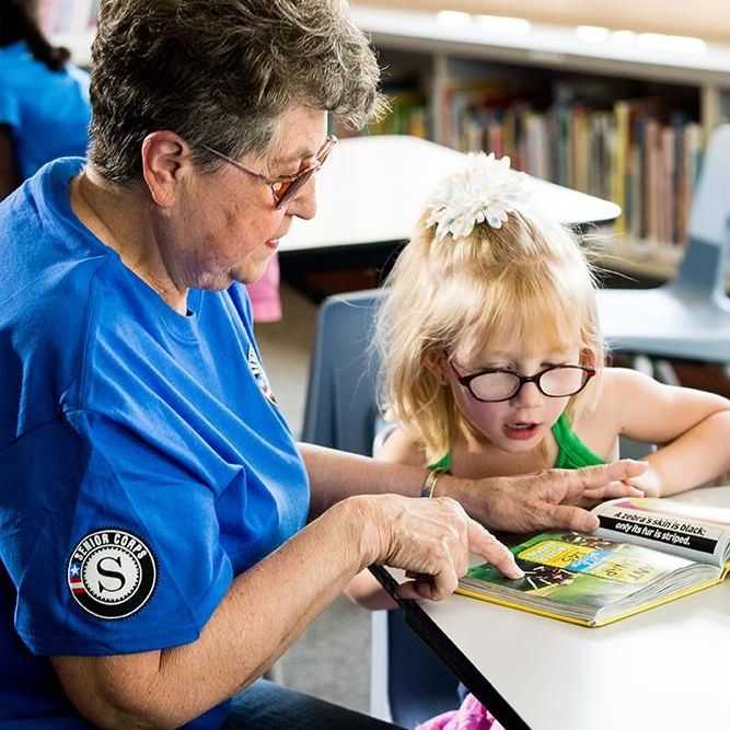 Older woman reading to a young child at a school.