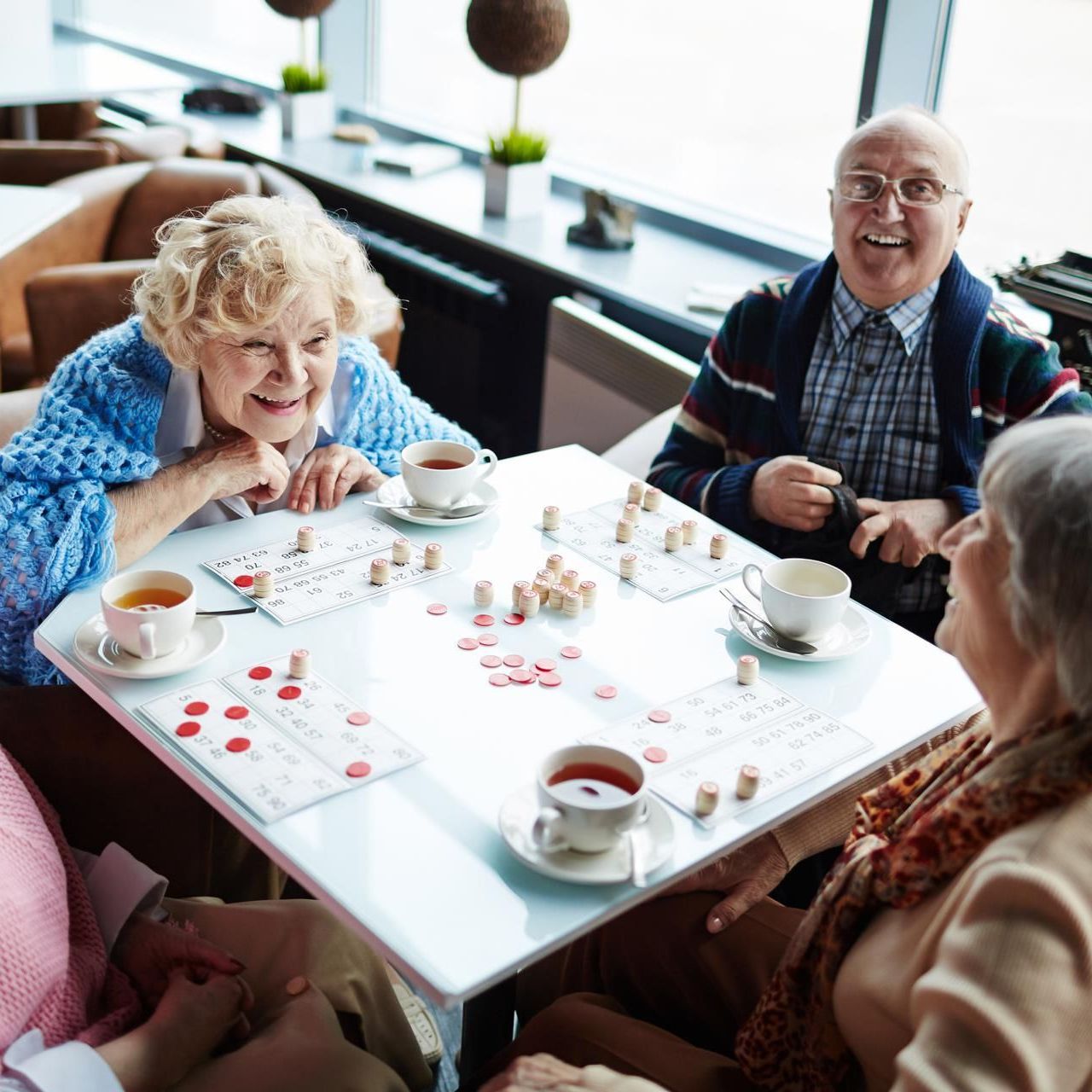 Group of elderly friends playing bingo in a public setting.